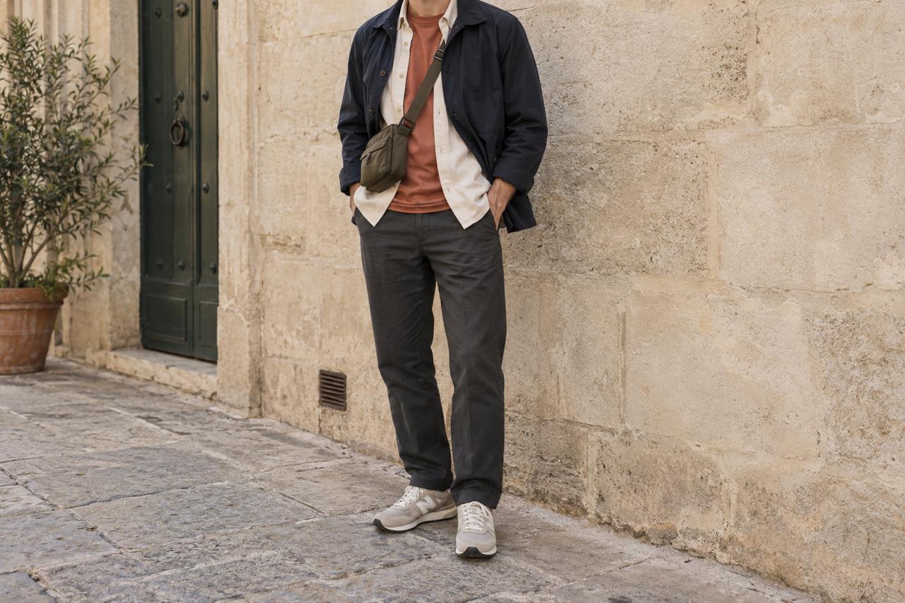 Conjunto de paseo con chaqueta azul abierta, camisa crema, camiseta teja, pantalón oscuro y zapatillas.